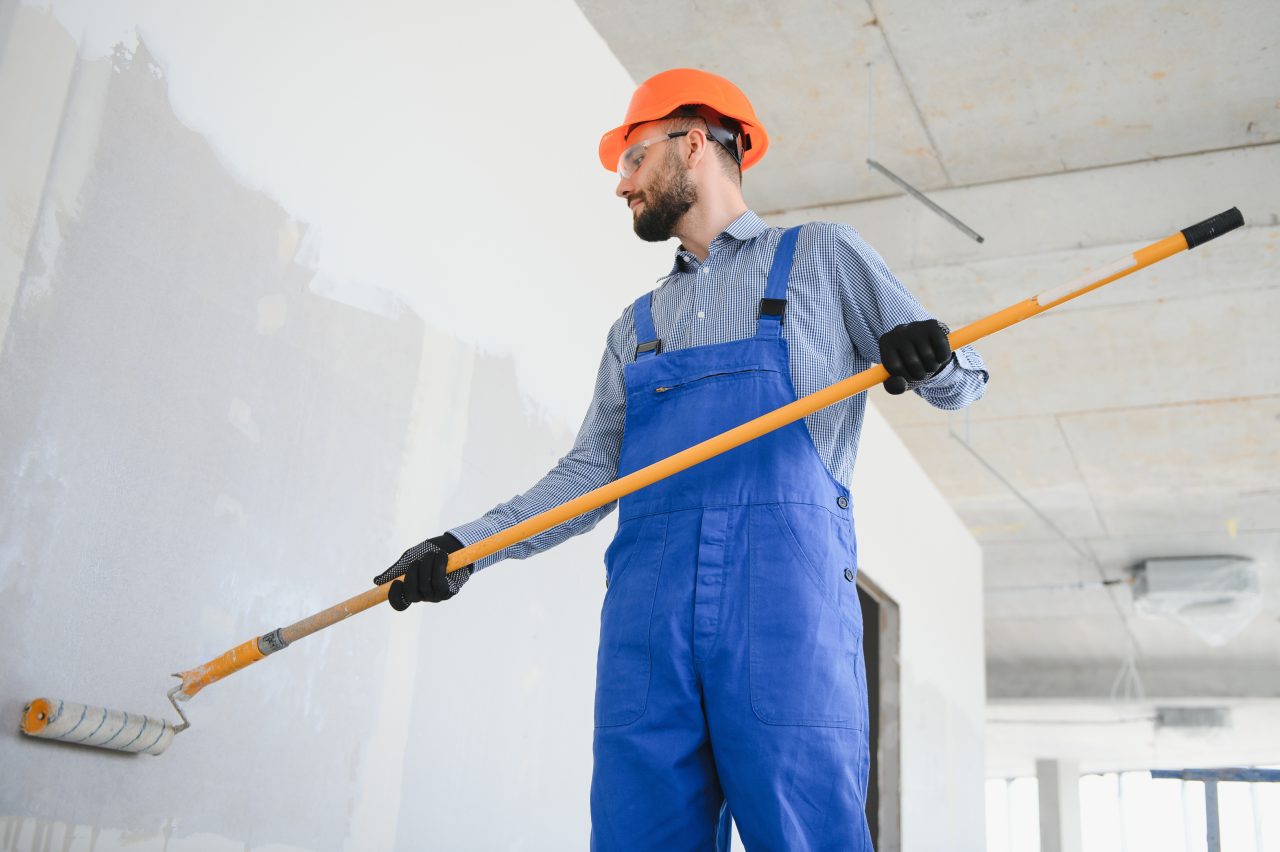 painter man painting the wall with paint roller e1698227409525