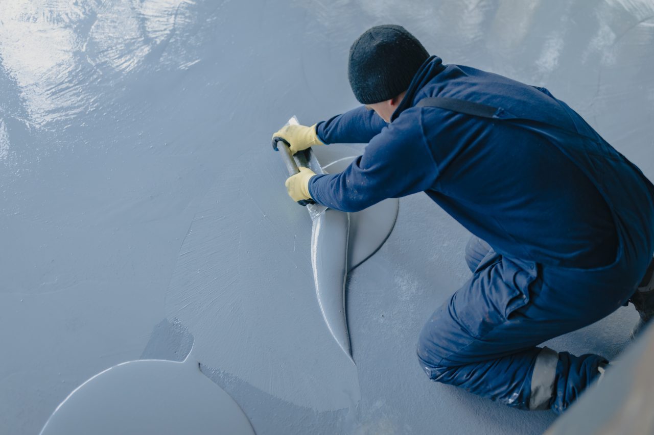 the worker applies gray epoxy resin to the new floor e1698216482312